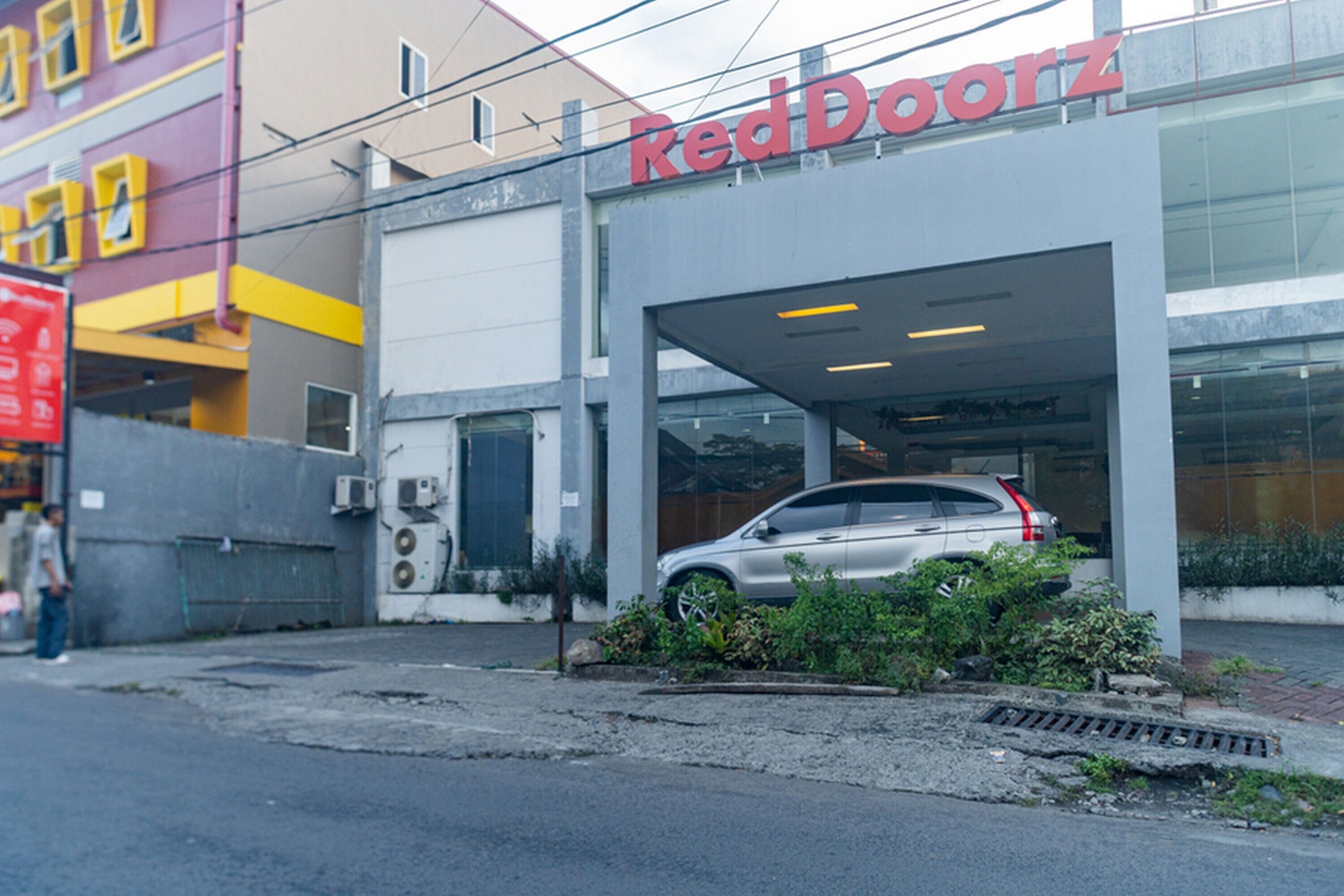 A RedDoorz building with a car parked in the garage.