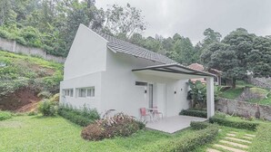 A modern white house with a sloped roof, a covered porch, and a small garden with a pathway leading to the entrance. - RedDoorz Resort Syariah @ Idelansia Homestay Ciater (Ciater)