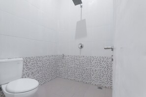 Ein Badezimmer mit Toilette, Dusche und Fliesen.
