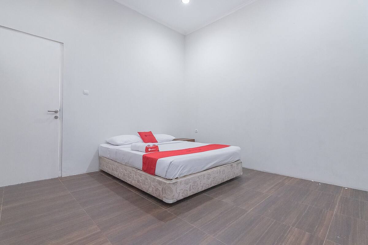 A bedroom with a bed, white walls, and a door.
