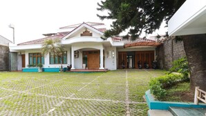 A house with a tiled roof, a front porch, and a paved courtyard. - RedDoorz Syariah near Alun Alun Magelang (Magelang)