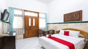 A hotel room with a bed, a desk, a chair, a television, and a door. - RedDoorz Syariah near Alun Alun Magelang (Magelang)