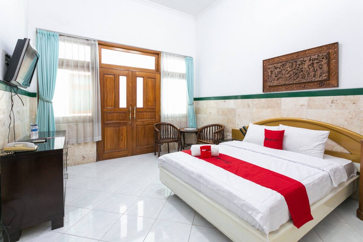 Une chambre d’hôtel avec un lit, un bureau, une chaise, une télévision et une porte.