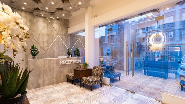 A reception area with a reception desk, patterned floor, and decorative plants. - RedDoorz Premium near Centre Point Mall Medan (Medan)