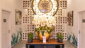 A lobby with a large decorative clock, a floral arrangement, and a no-smoking sign. - RedDoorz Premium near Centre Point Mall Medan (Medan)