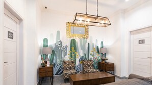 A modern living room with a cactus-themed mural, a wooden coffee table, patterned armchairs, and a hanging light fixture. - RedDoorz Premium near Centre Point Mall Medan (Medan)