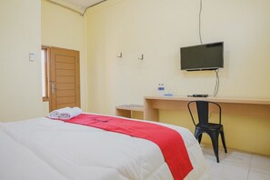 Une chambre d’hôtel avec un lit, un bureau, une chaise, une télévision et une porte.