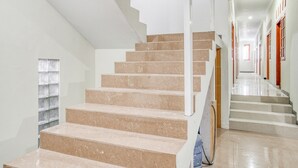 Eine Treppe mit beigen Stufen und weißen Geländern, die zu einer Empore führt.