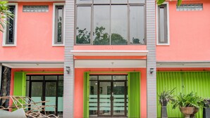 Ein Gebäude mit einer rosafarbenen Fassade, großen Fenstern und grünen Fensterläden.