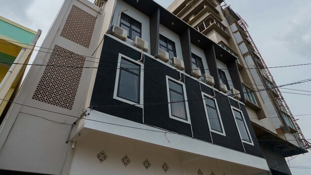 Un edificio de varios pisos con un diseño arquitectónico moderno, que cuenta con balcones y unidades de aire acondicionado.