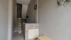 Un pasillo con mostrador de recepción, una escalera y un reloj en la pared.
