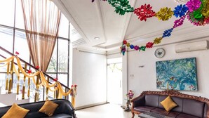 Eine großzügige Lobby mit einem schwarzen Ledersofa, einem Holztisch und einer Treppe mit goldenen Vorhängen.