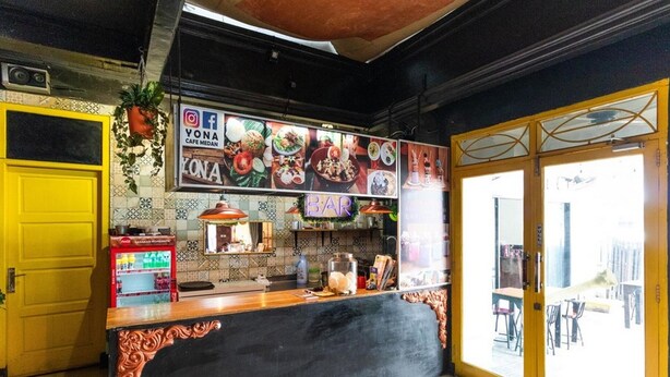 Ein Restaurant mit einer schwarzen Theke, einer gelben Tür und befliessten Wänden.