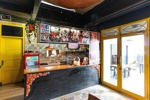 En restaurang med en svart bardisk, en gul dörr och kakelbeklädda väggar.