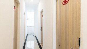 A clean, modern hallway with a black and white tiled floor, wooden doors, and a visible room number '202' on the right. - RedDoorz Plus @ Centrium Katamso Medan (Medan)