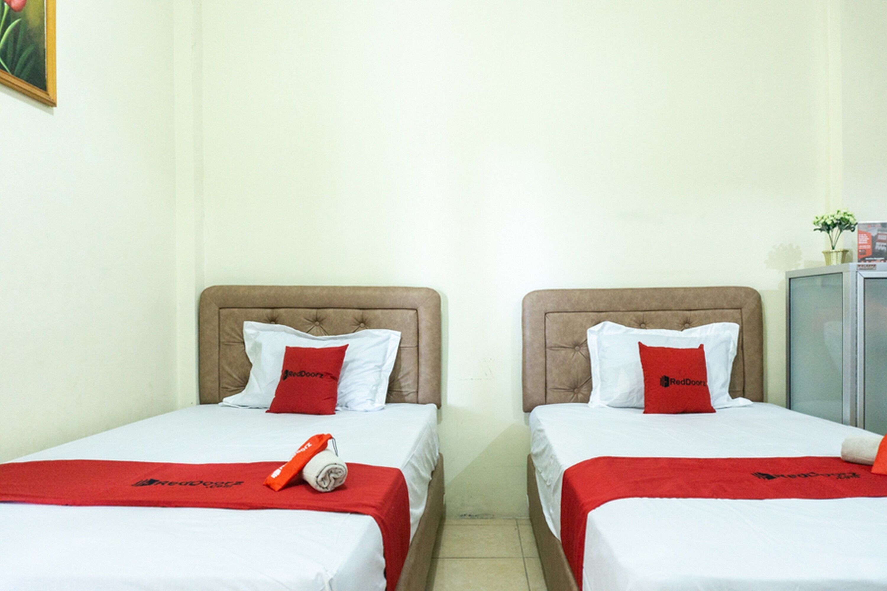 Two single beds with headboards, white bedding, and red accents.