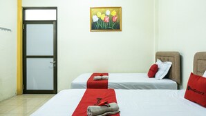 Een hotelkamer met twee eenpersoonsbedden, een deur en een tulpenbloemschilderij aan de muur.