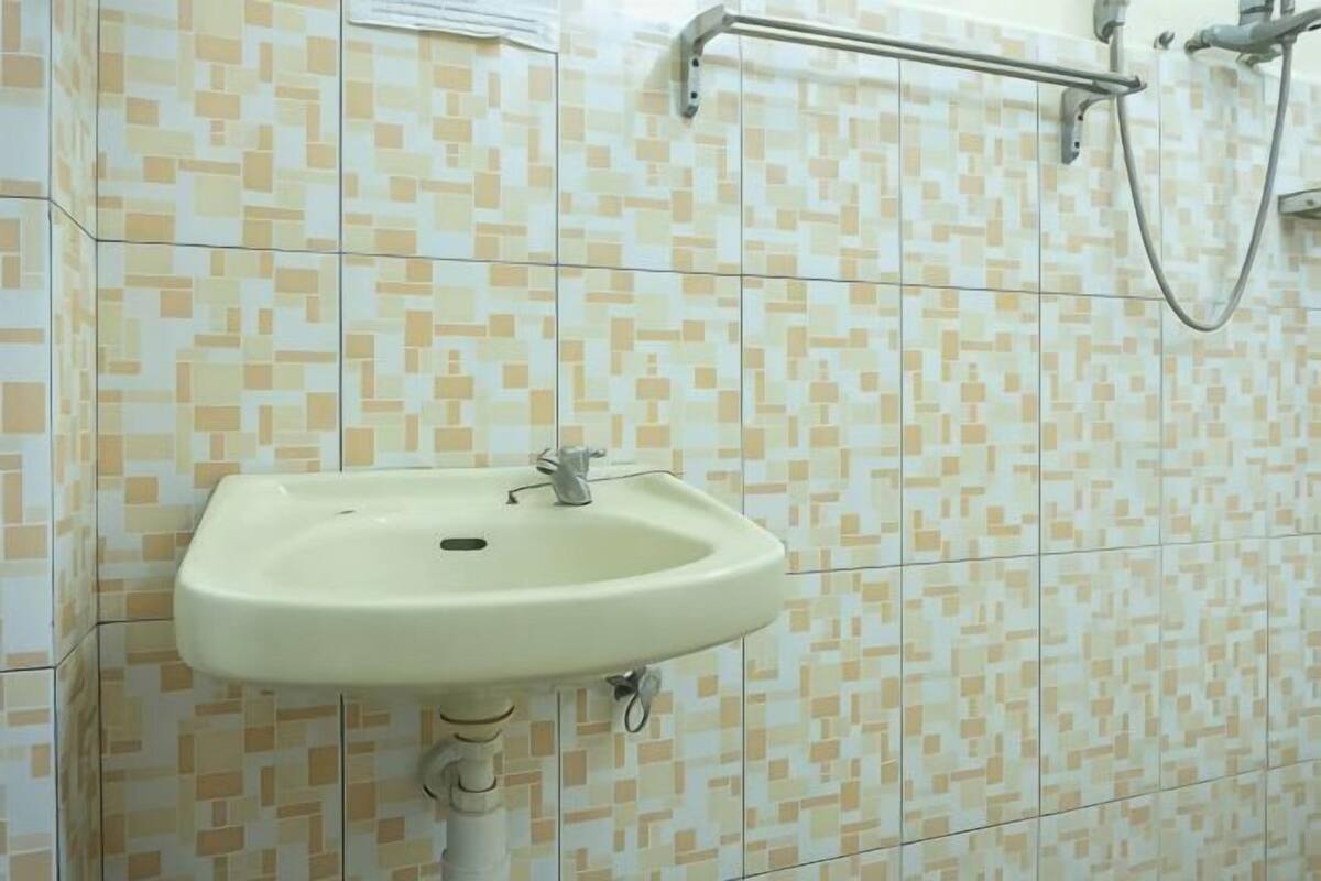 Un baño con lavamanos, paredes con azulejos y ducha.