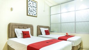 Dos camas individuales con cabeceras, ropa de cama blanca y detalles en rojo.