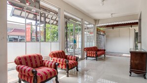 A spacious room with large windows, two armchairs, and a wooden cabinet. - RedDoorz near Malioboro Tugu Station Jogja 2 (Yogyakarta)