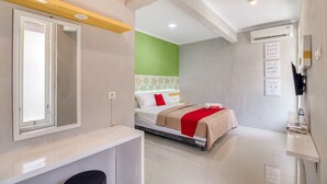 A modern hotel room with a bed, a bedside table, a mirror, and a wall-mounted TV. - RedDoorz near Malioboro Tugu Station Jogja 2 (Yogyakarta)
