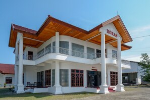Un edificio de dos pisos con fachada blanca, techo de madera y balcones.