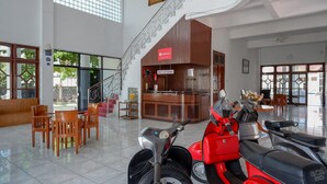 Un vestíbulo amplio con mostrador de recepción, una escalera y un comedor con mobiliario de madera.