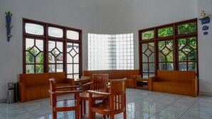 Una habitación amplia con ventanas grandes, un sofá de madera y una mesa de comedor con sillas.