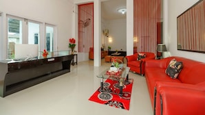 Una sala de estar moderna con un sofá rojo, una mesa de centro de vidrio y un mostrador de recepción.