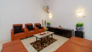 Una sala de estar moderna con sofás naranja, una mesa de centro y un mueble para televisión.