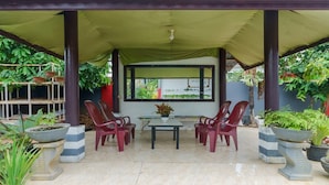 Un patio al aire libre con un área de estar techada, una mesa y plantas en macetas.