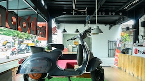 Een scooter staat binnen in een gebouw met een groene vloer, een RedDoor bord en een RedDoor logo aan de muur.