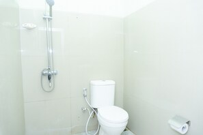 A bathroom with a toilet, a shower, and a toilet paper holder.
