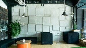 Een moderne lounge met een geometrisch wandontwerp, zwarte bekleding en een houten salontafel.