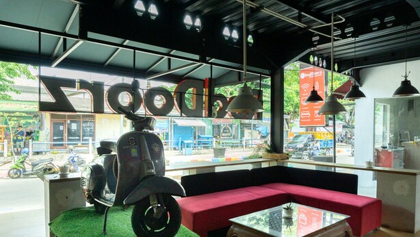 Een modern interieur met een rode bank, een glazen tafel, en een scooter met een zitplaats in de band.