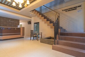 A reception area with a desk, chairs, and a staircase.