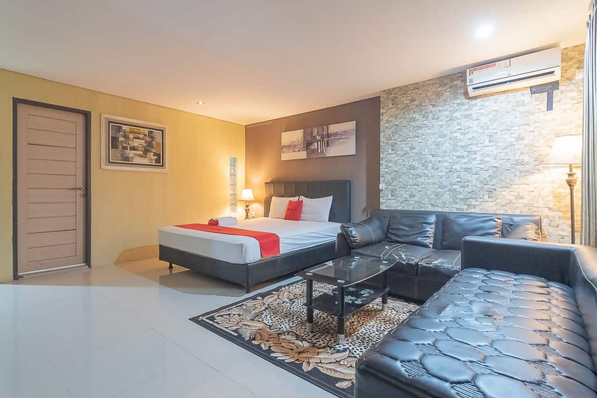 Una habitación de hotel moderna con una cama, un sofá, una mesa de centro y una alfombra.