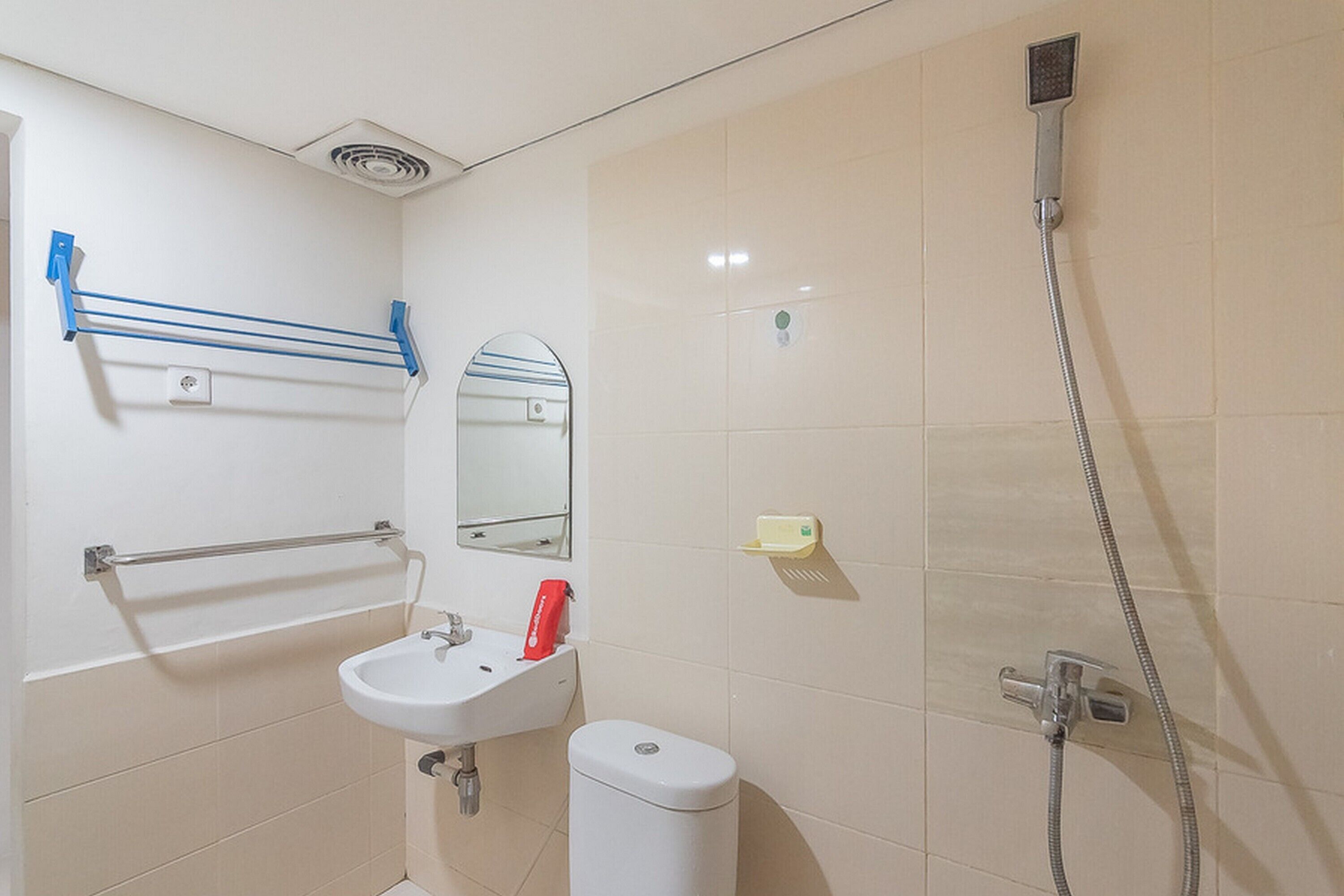 Ein Badezimmer mit Waschbecken, Spiegel, Handtuchhalter, Toilette und Dusche.