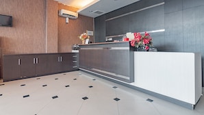 A modern reception area with a reception desk, wooden panel walls, and a tiled floor. - RedDoorz near Stadion Sanaman Mantikei (Palangkaraya)