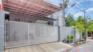 A gated residential area with a covered entrance, a paved walkway, and potted plants. - RedDoorz near Surabaya Zoo (Surabaya)