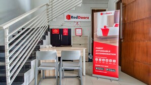 A reception area with a staircase, a reception desk, two chairs, and a RedDoorz advertisement. - RedDoorz near Surabaya Zoo (Surabaya)