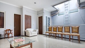A spacious living room with a glass coffee table, a white sofa, and a row of leather chairs. - RedDoorz near Surabaya Zoo (Surabaya)