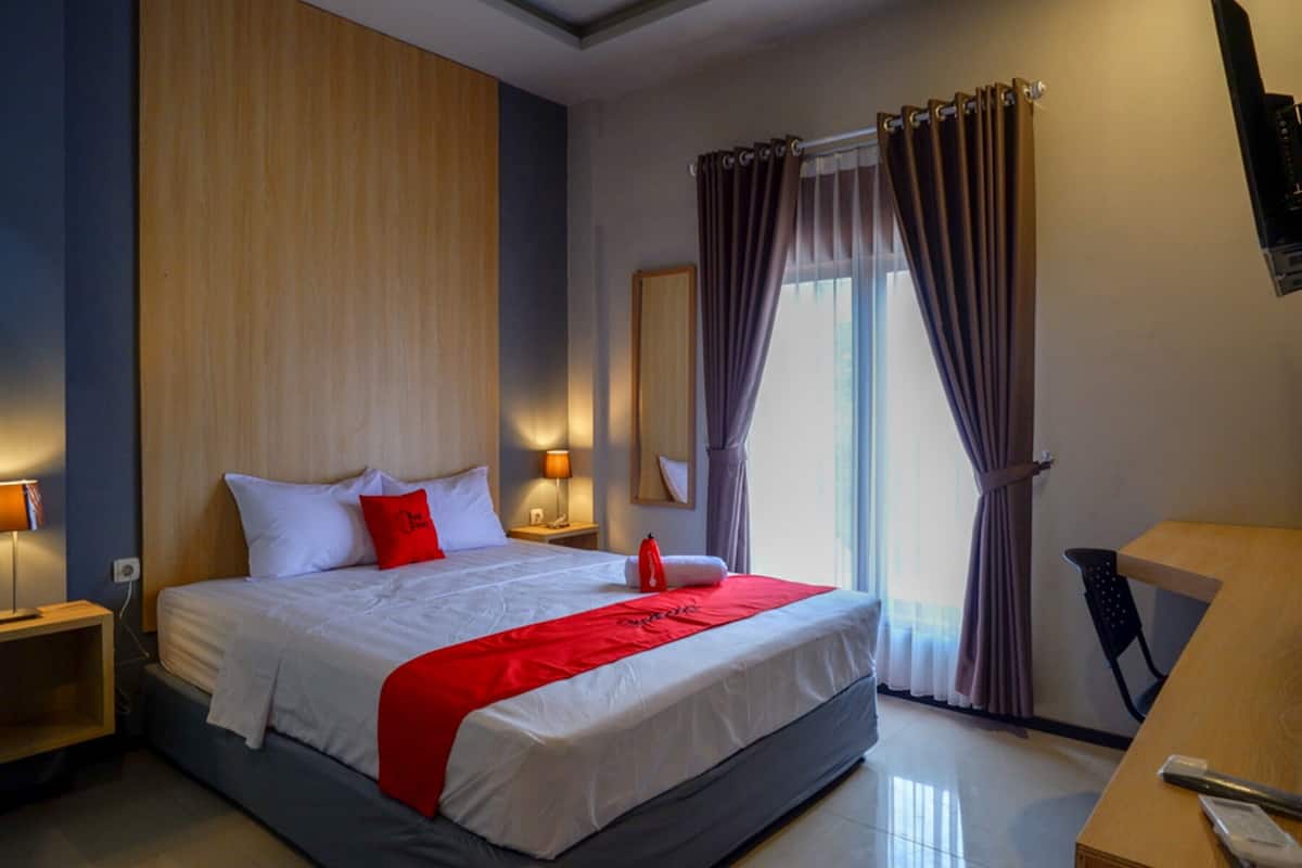 A hotel room with a large bed, two bedside tables, a desk, and a chair.