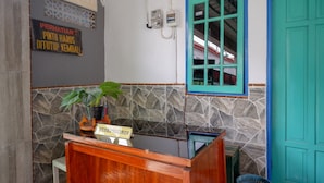 A reception desk with a sign reading "PERSIONSIS" and a potted plant. - RedDoorz Syariah near Alun Alun Balai Kota Tegal (Tegal)