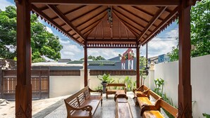 A covered outdoor seating area with wooden benches and a tiled floor. - RedDoorz Syariah near Exit Toll Banyumanik (Semarang)