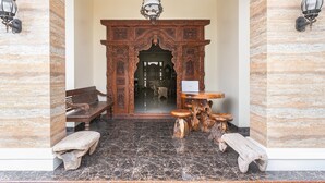 A lobby with a marble floor, a wooden bench, a wooden table, and a decorative wooden archway. - RedDoorz Syariah near Exit Toll Banyumanik (Semarang)