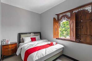 A bedroom with a bed, wooden wardrobe, and a window with a view of greenery. - RedDoorz Syariah near Exit Toll Banyumanik (Semarang)