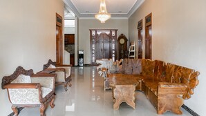 A spacious lobby with a chandelier, wooden furniture, and a large wooden sofa. - RedDoorz Syariah near Exit Toll Banyumanik (Semarang)