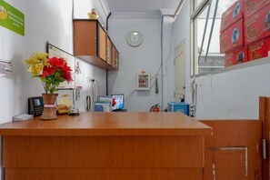 Ein Empfangsbereich mit einer Uhr, einem Telefon und einer Blumenvase.