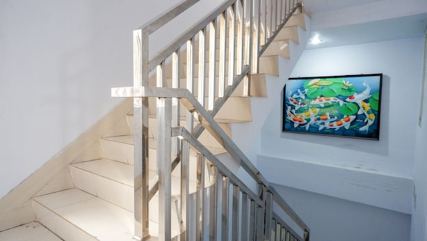 A staircase with a metal railing and a painting on the wall above it. - RedDoorz @ Hotel Bravo Pantai Kamali Bau Bau (Bau-Bau)
